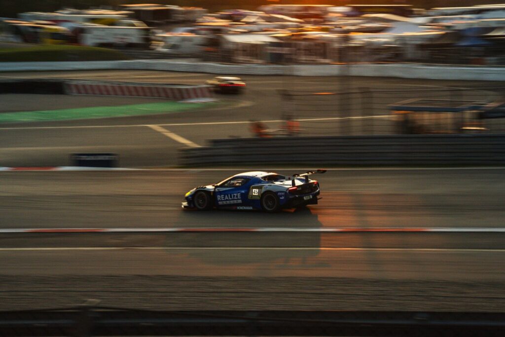 Race car speeds down a track at sunset.